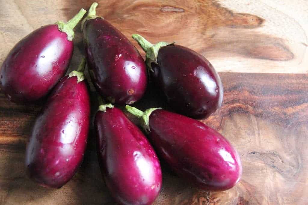 6 baby eggplant on a wooden cutting board 