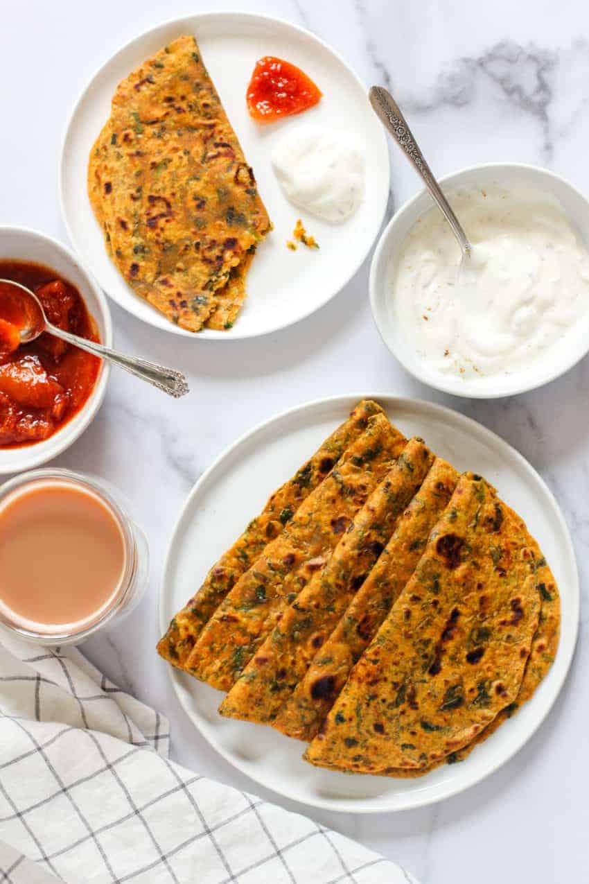 Methi Thepla in a white plate with yogurt and pickle on the side