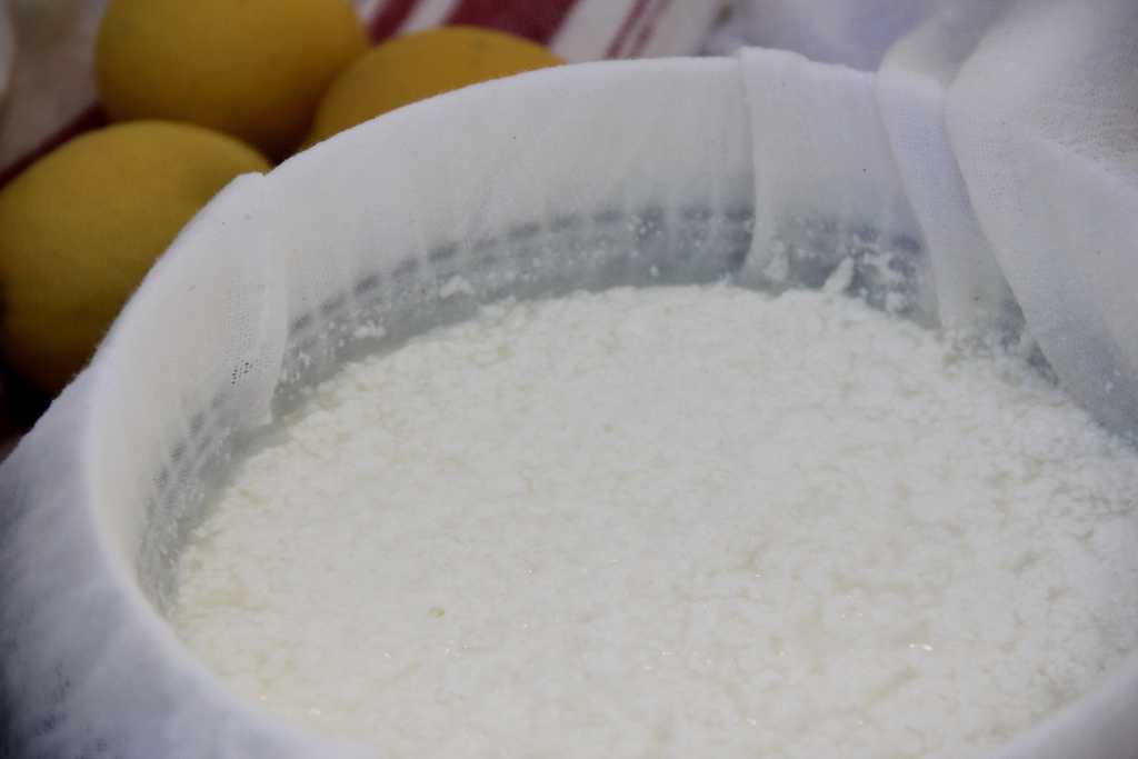 curdled milk poured in a bowl lined with cheesecloth