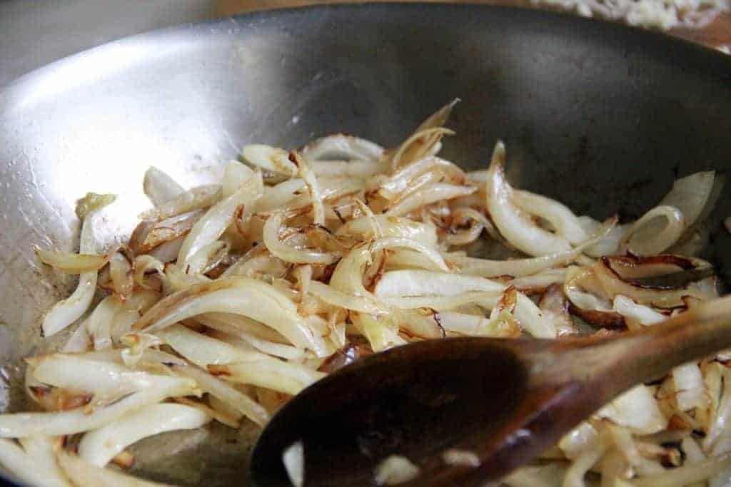 onions being sauteed in a pan 