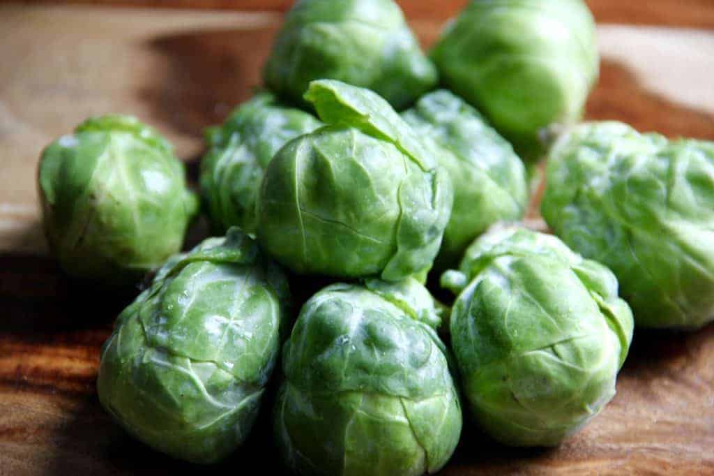 whole brussels sprouts on a wooden cutting board