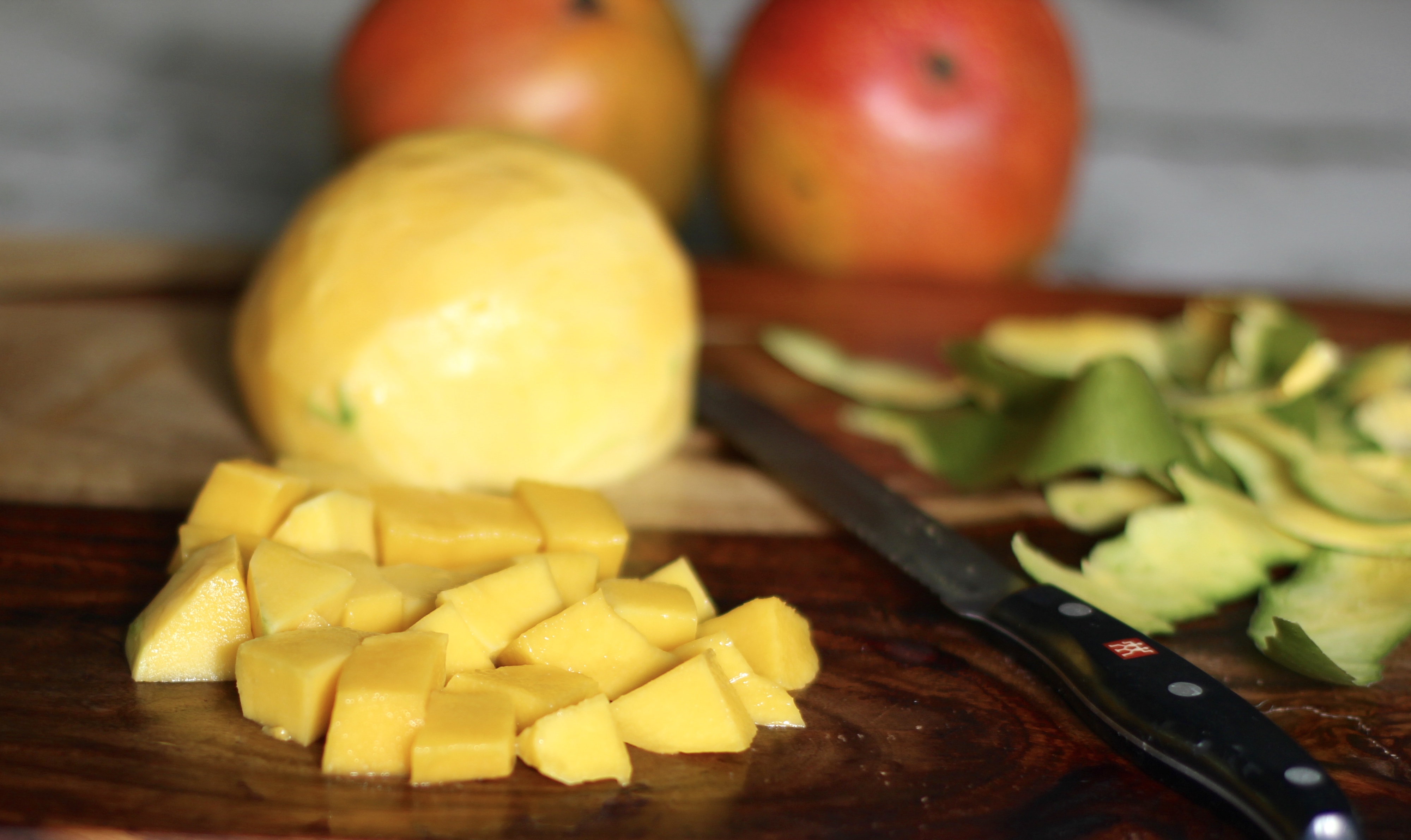 mango cut up on a wooden cutting board with knife