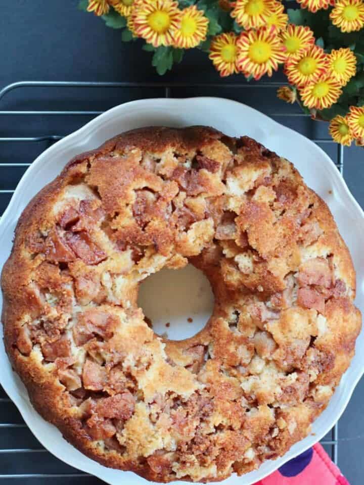 apple cake in a white plate with mini mums on the side