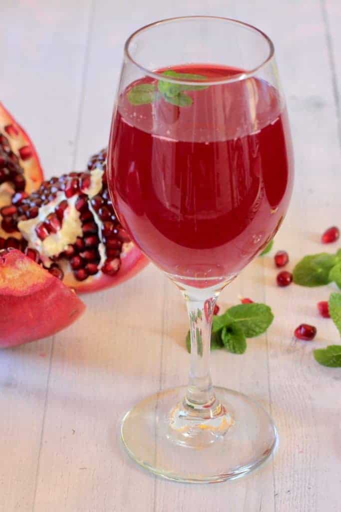pomegranate juice in a wine glass with mint leaves