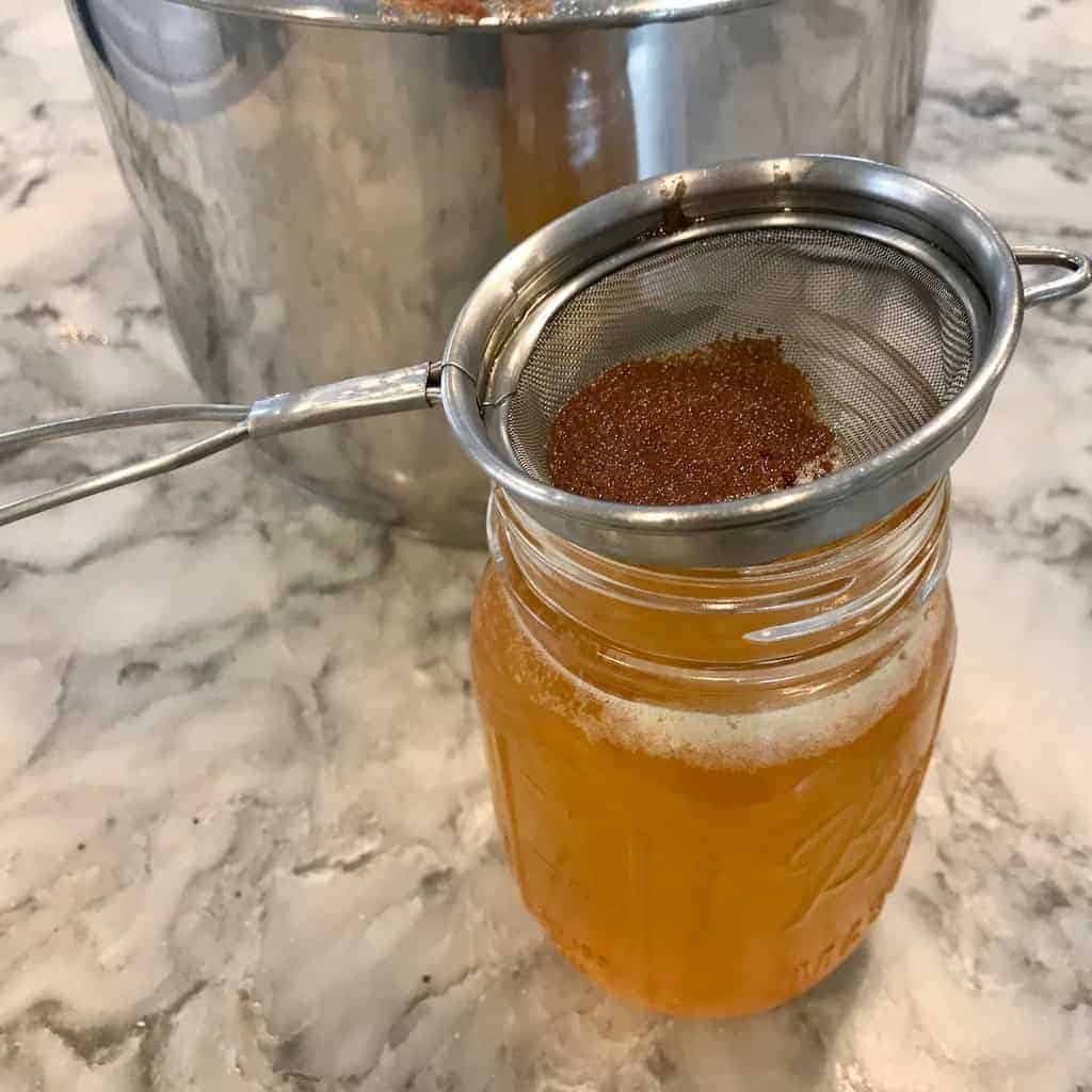 straining ghee in a glass jar 