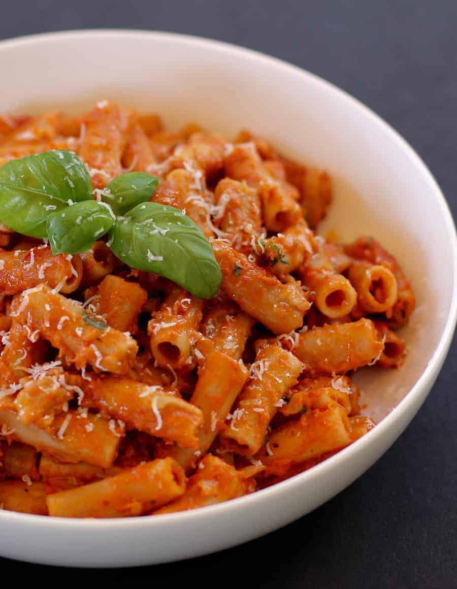 penne alla vodka in a white bowl garnished with basil 