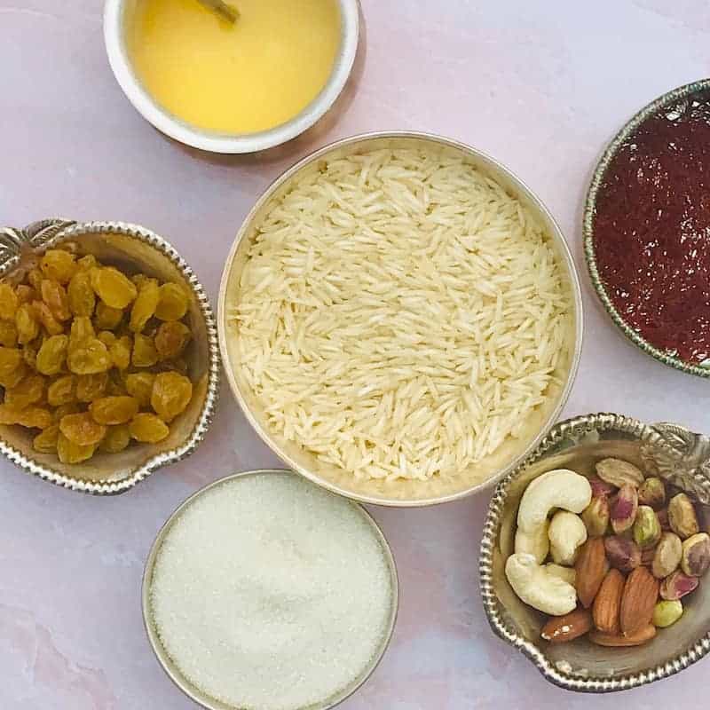 Ingredients for rice pudding in bowls - rice, nuts, sugar, raisins, ghee and saffron 