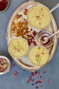 Rice Pudding served in 3 silver bowls in a silver tray with raisins, nuts and saffron in bowls