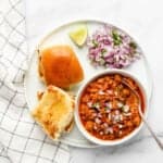 Kheema curry served with buttery buns, diced onions and lemon
