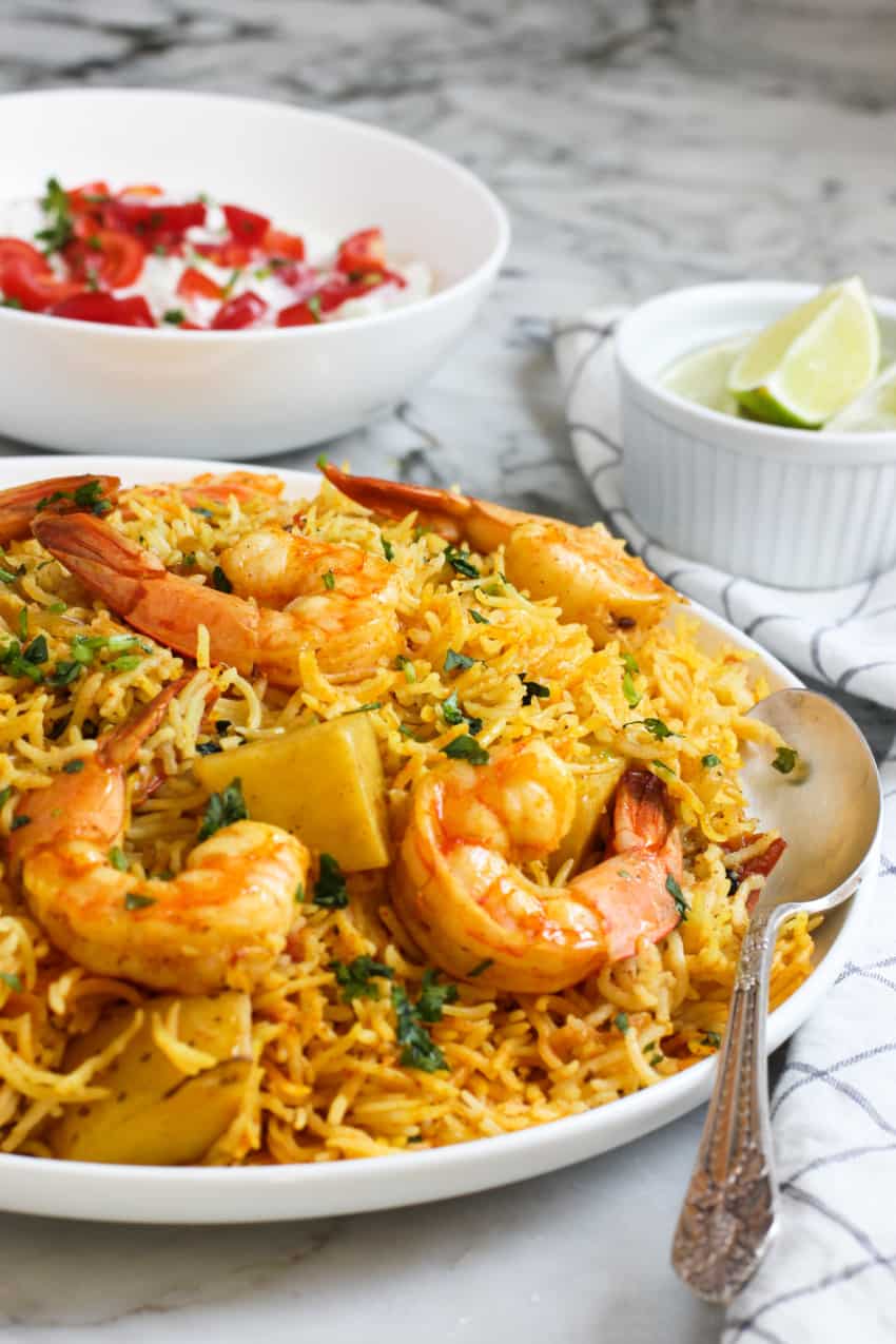 shrimp biryani served with raita and lime wedges