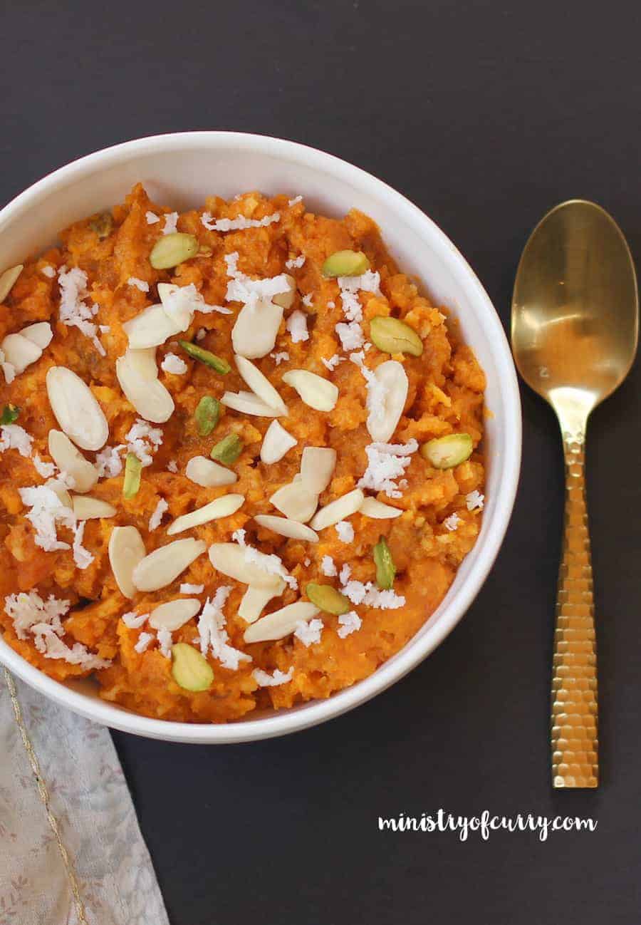 sweet potato halwa in a white bowl garnished with nuts and shredded coconut 