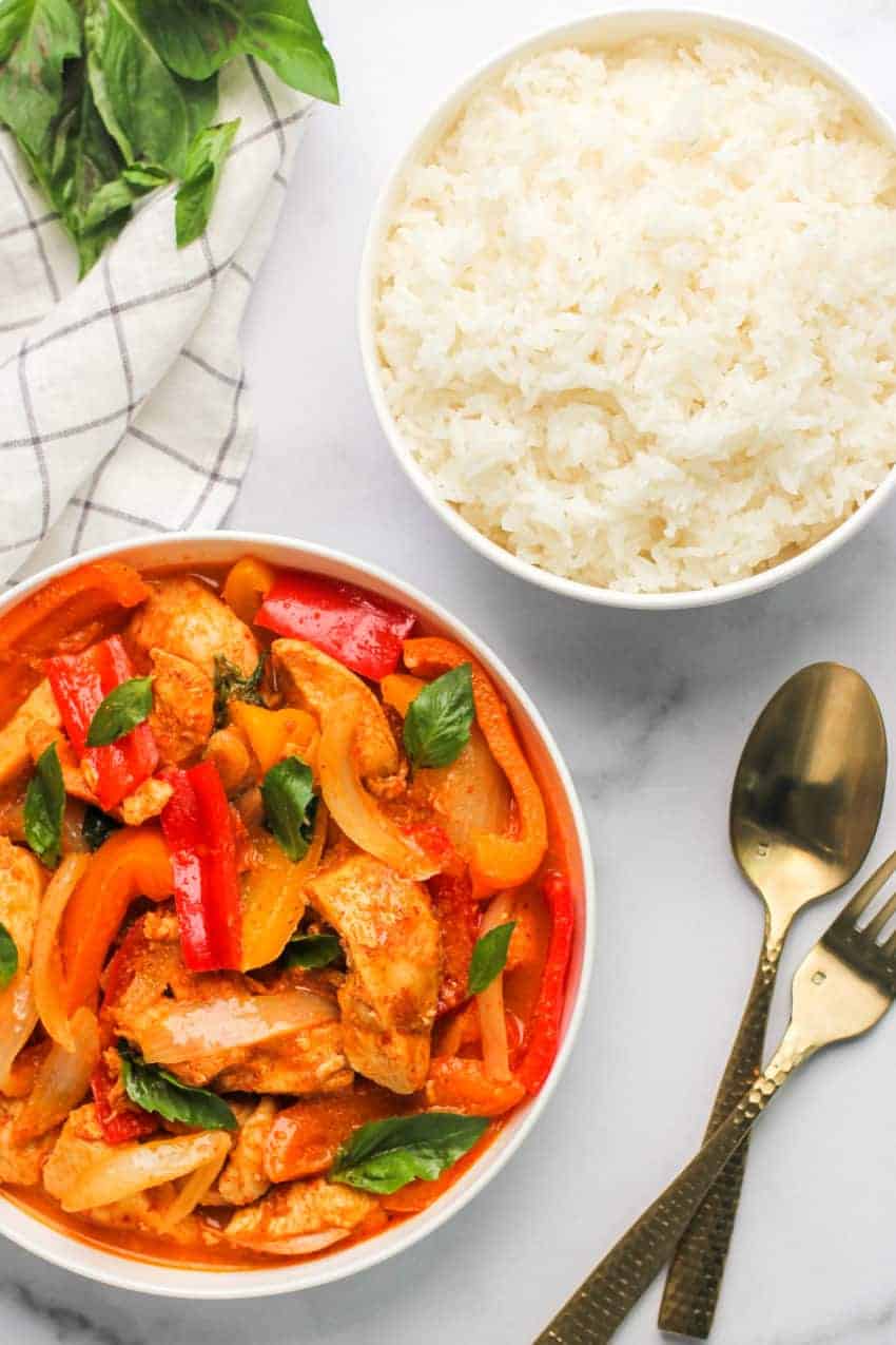 Thai Red Curry Chicken in a white bowl with rice on the side