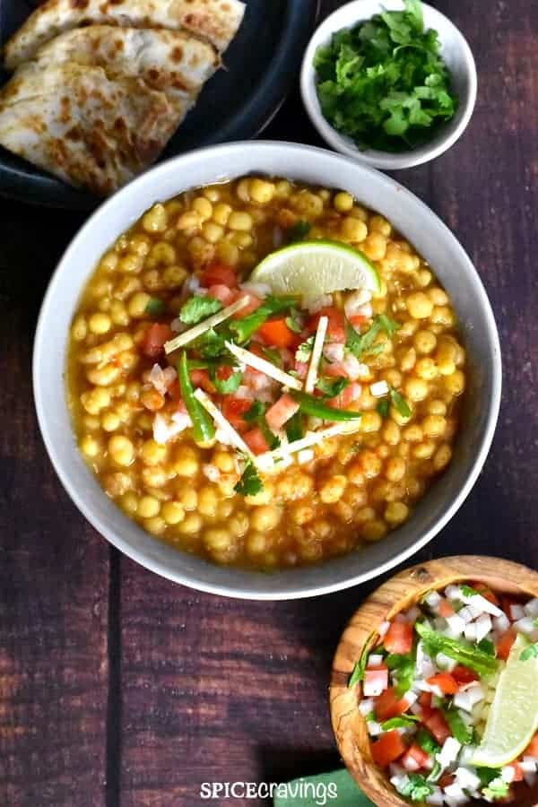 Matar Chaat Served in a bowl garnished with onions, cilantro and lime wedge