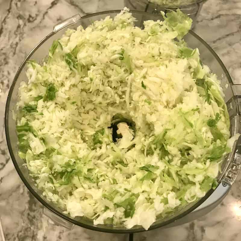 grated cabbage in a food processor bowl 