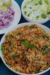 White Bowl with Chickpea Biryani. Two small white bowls on the side with cucumber raita and diced onions