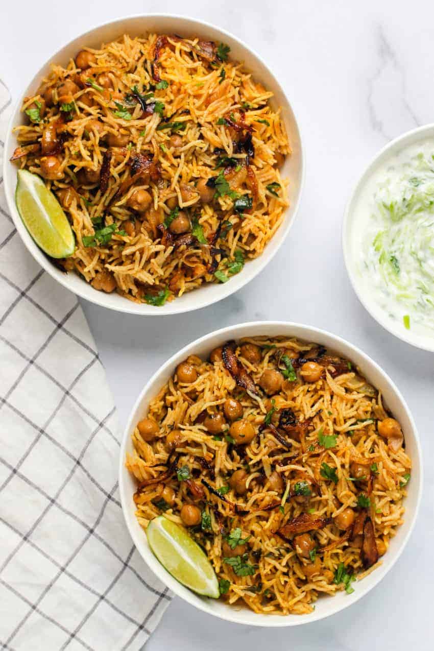 two bowls of chickpea biryani and raita on the side