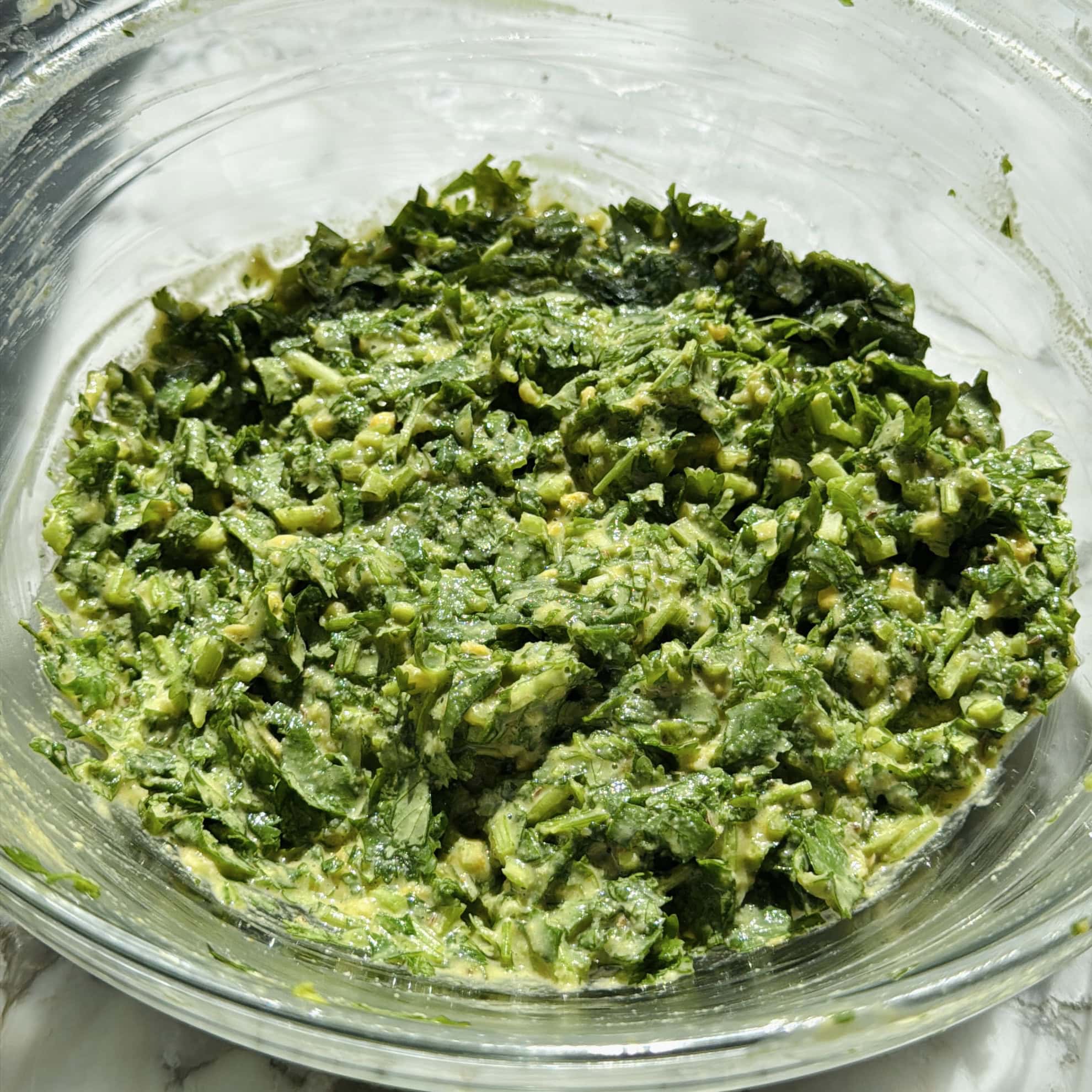 A glass bowl filled with kothimbir vadi batter.