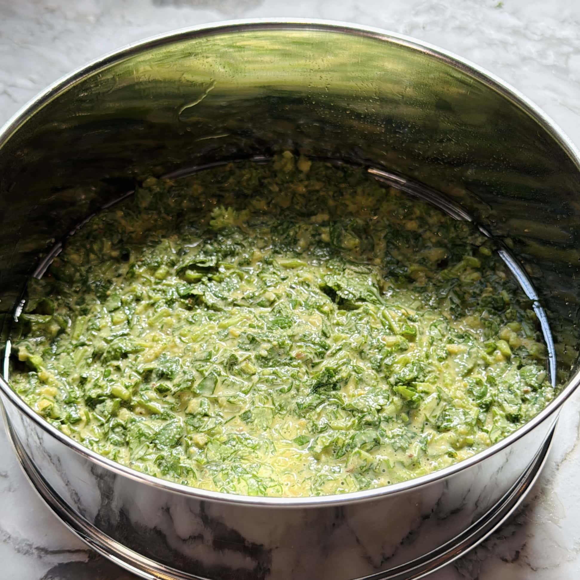 A round metal pan filled with kothimbir wadi batter.