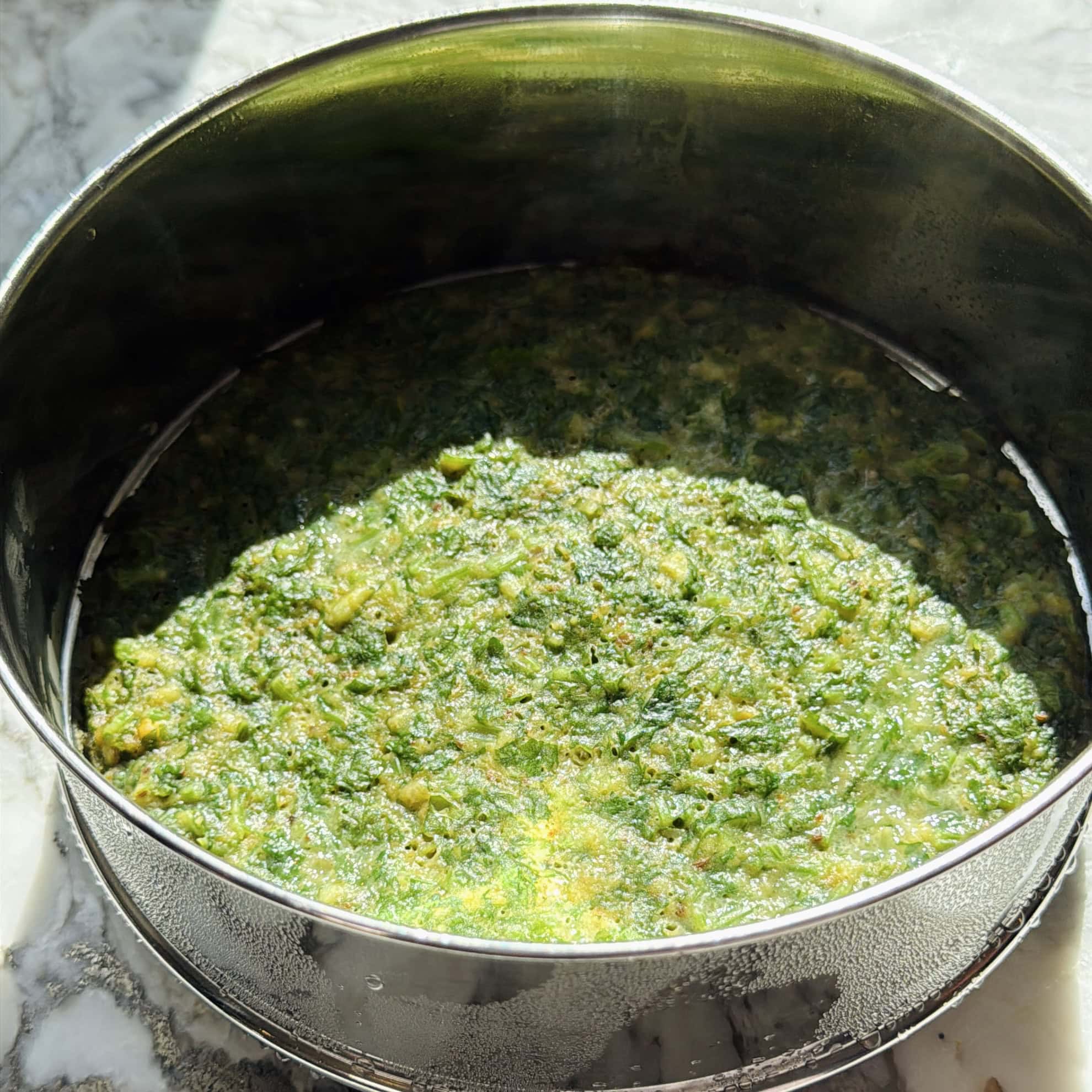 A round metal pan filled with steamed kothimbir vadi batter.