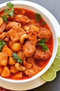 Thai Massaman Chicken Curry in a white bowl with sliced lime on the side