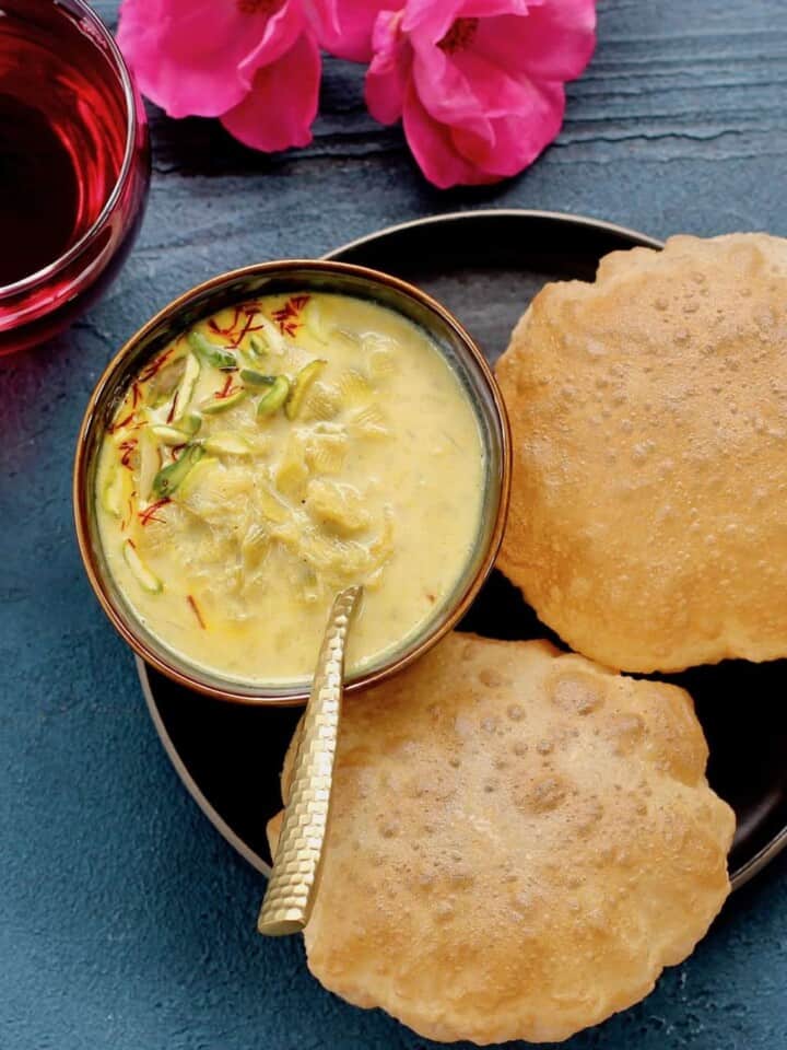 Dudhi Basundi in a bowl with puffed pooris served on the side