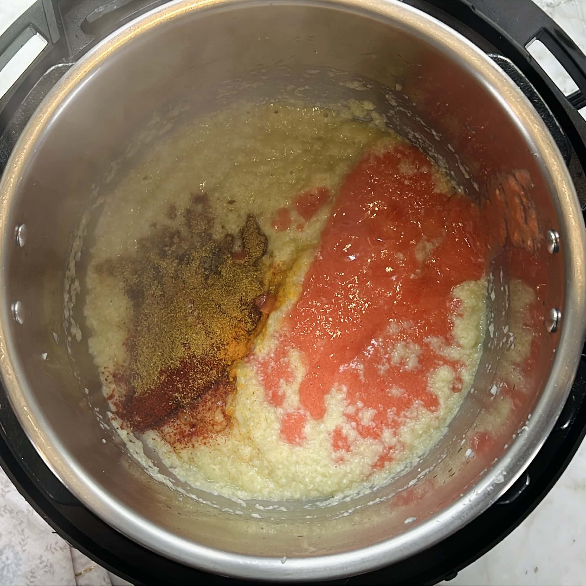 adding ground spices and tomato paste to the sauteed onion and coconut paste.