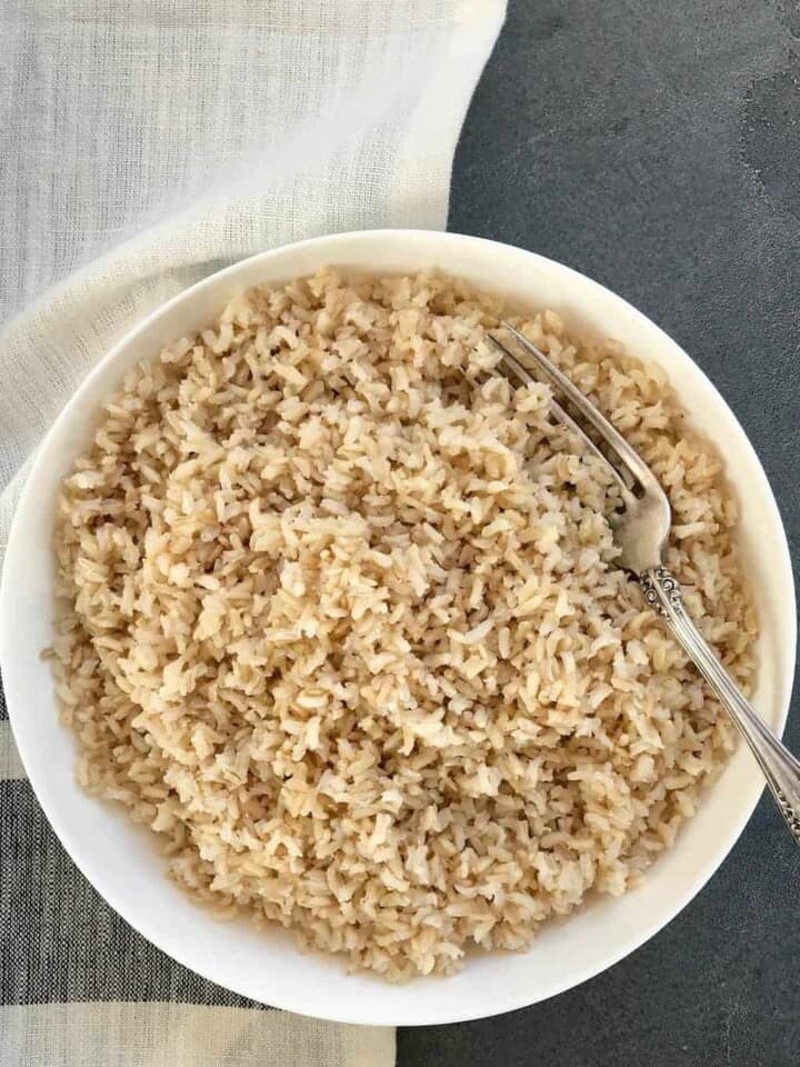 Cooked Brown rice in a white bowl with a fork