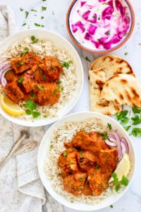 Chicken Tikka Masala served over white rice with naan and raita on the side