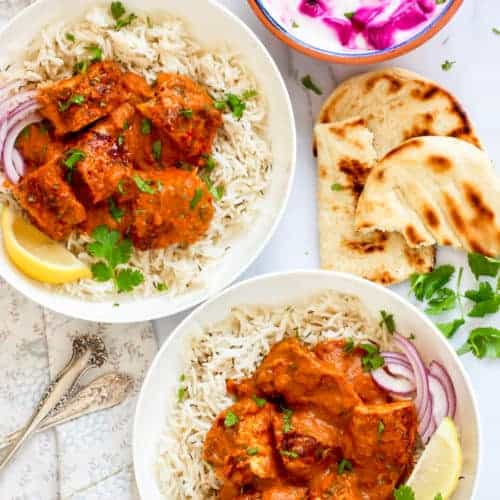 Chicken Tikka Masala served over white rice with naan and raita on the side