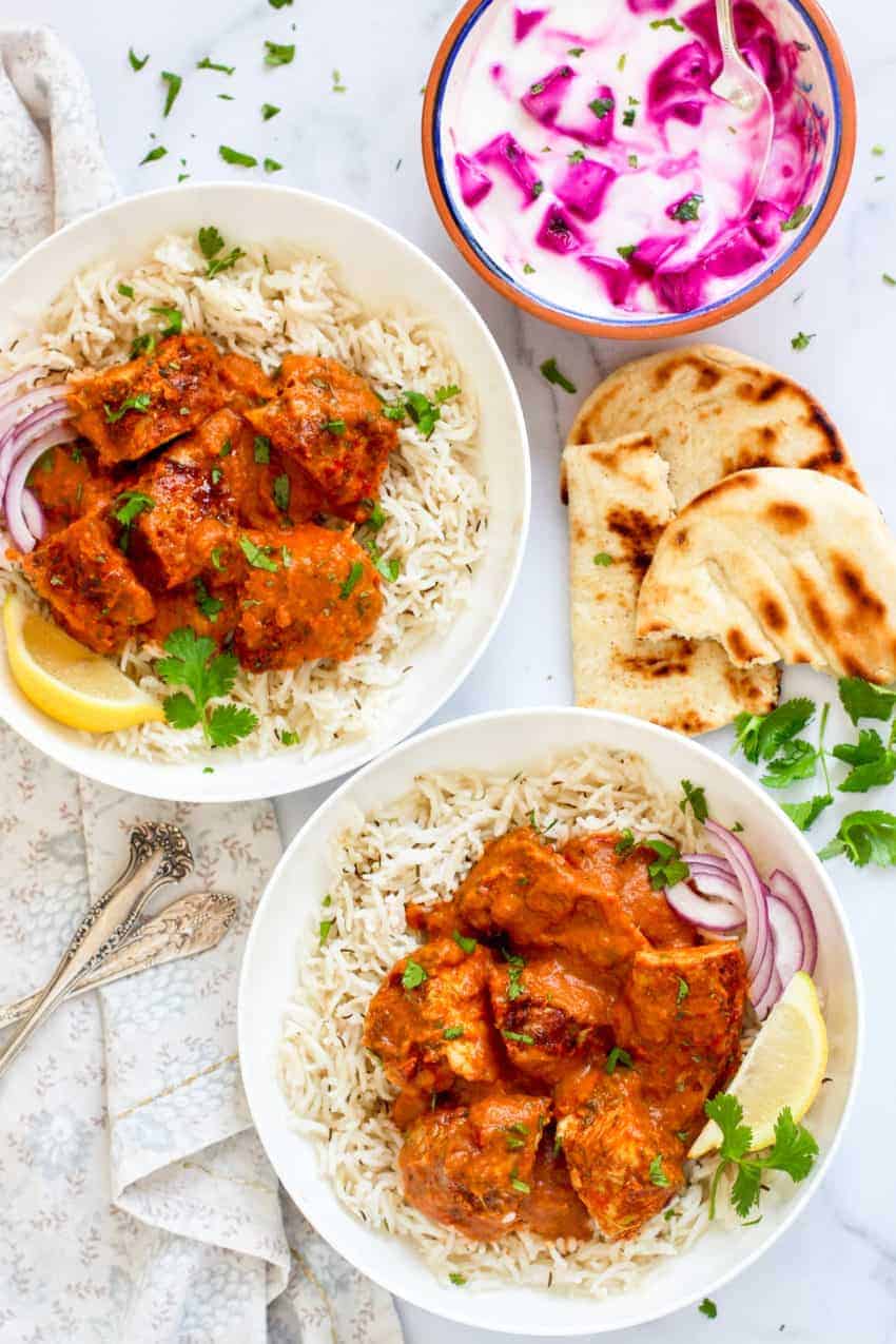 Chicken Tikka Masala served over white rice with naan and raita on the side 