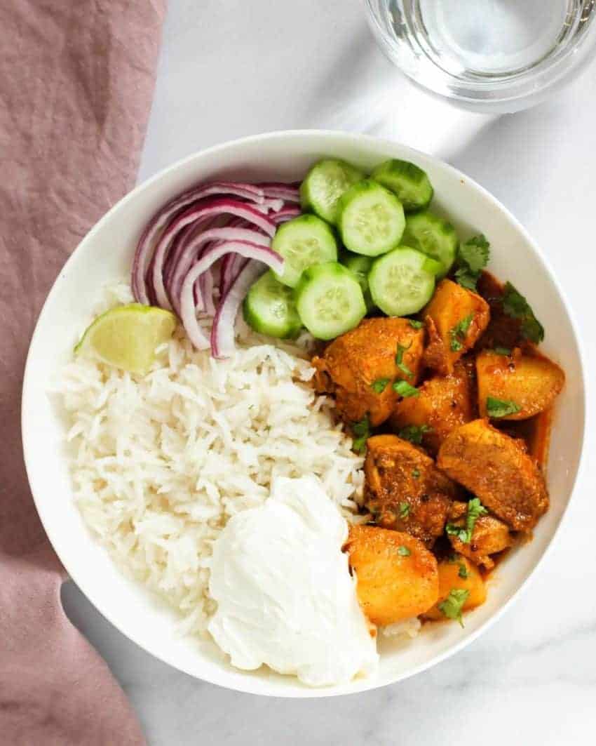 Chicken vindaloo curry served with rice, sliced onions and cucumber. 