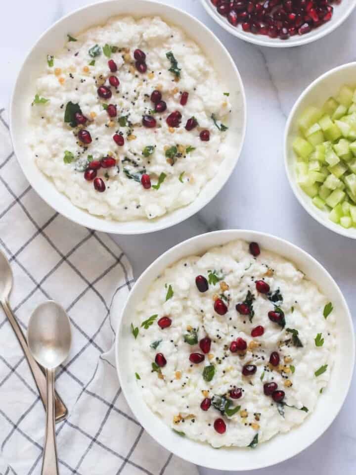 Curd Rice in 2 bowls garnished with cilatro and pomegranate seeds