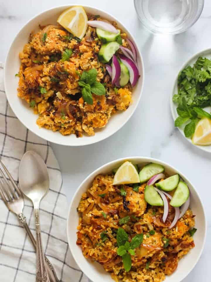 cauliflower rice chicken biryani in 2 white bowls