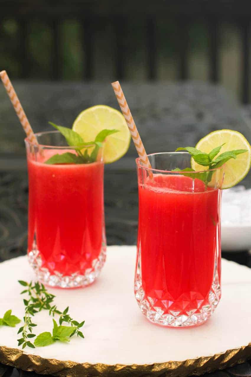 watermelon juice garnished with mint and lime in two glass cups 