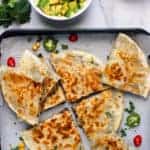 quesadillas on a tray with avocado and salsa on the side