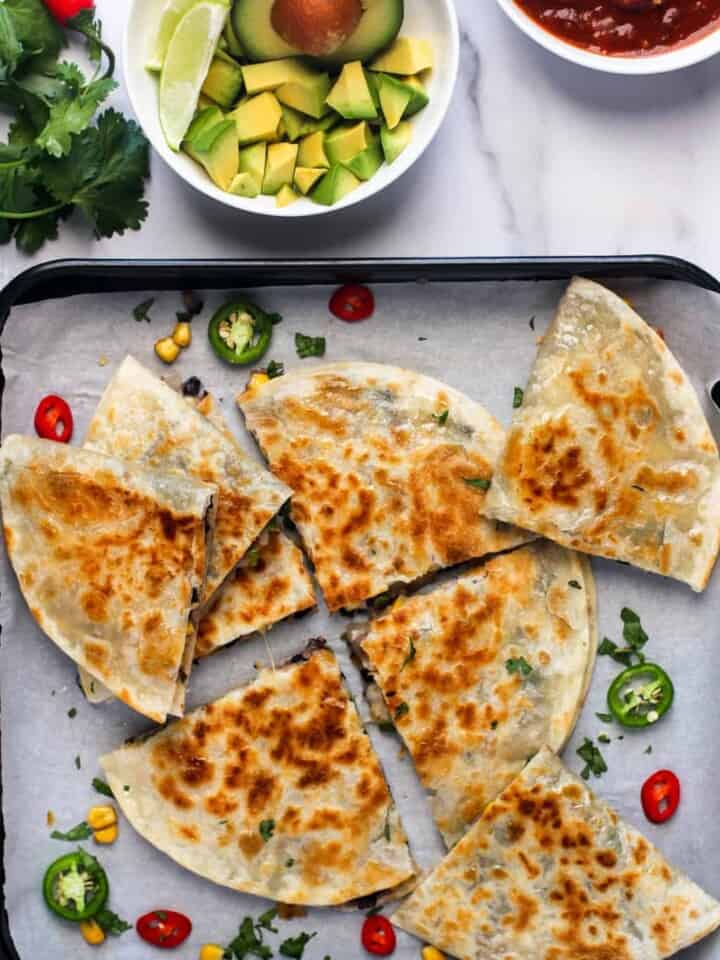 quesadillas on a tray with avocado and salsa on the side