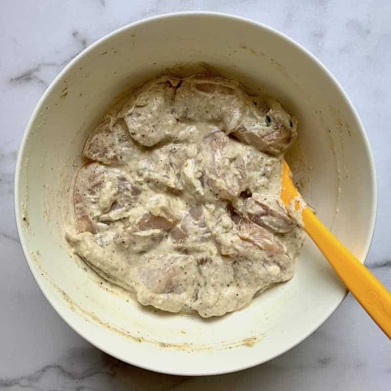 marinated chicken in a white bowl 