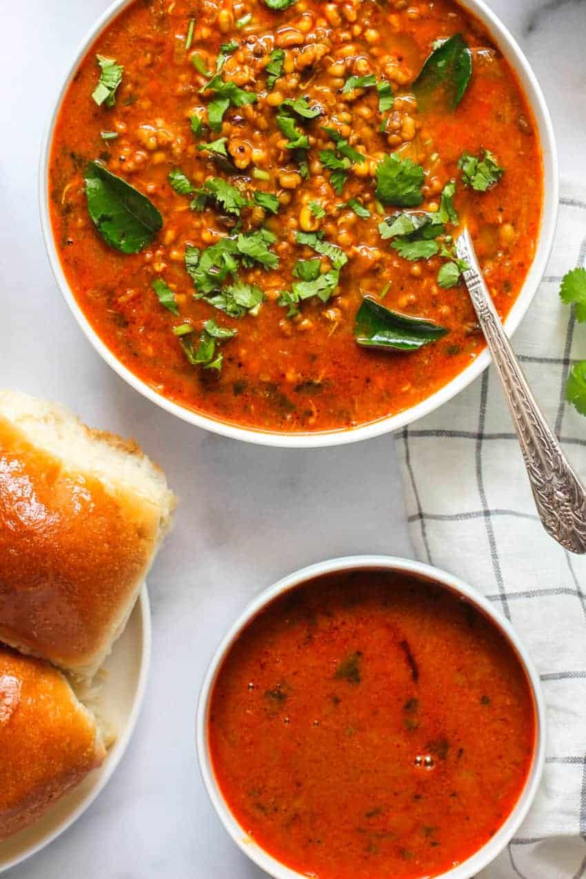 Sprouted bean curry in a big bowl, gravy in a smaller bowl and rolls on the side 