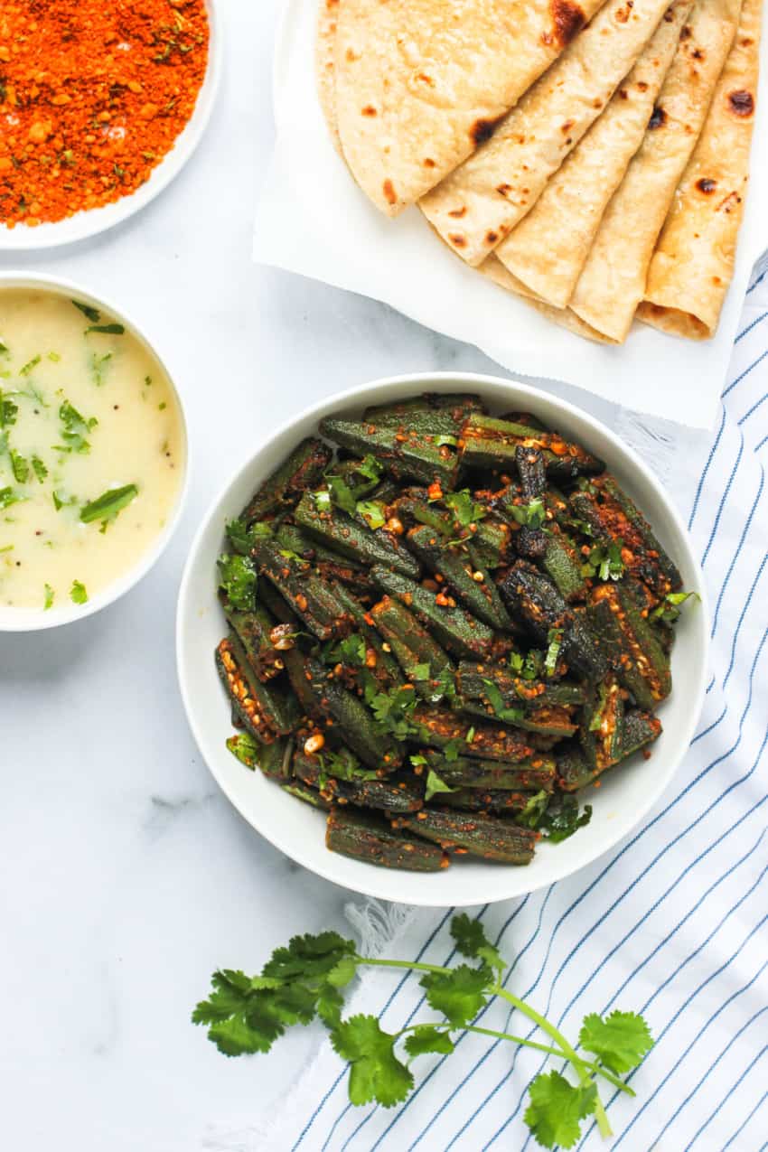 Stuffed okra in a white bowl with roti's on the side 