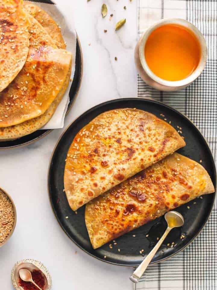 Tilachi Poli in a black plate with ghee on the side