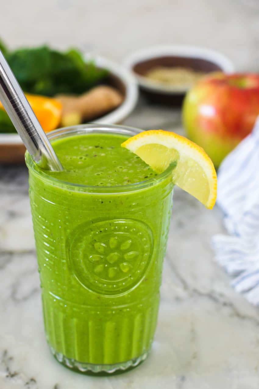 green smoothie in a glass with lemon wedge 