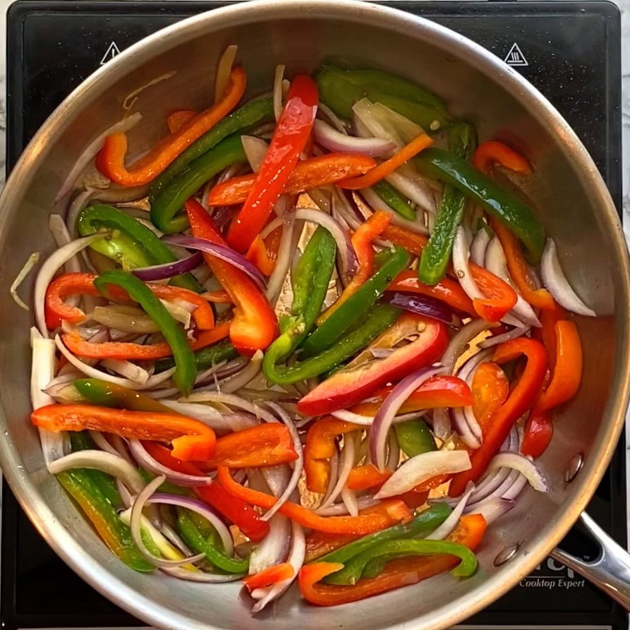 sauteeing onions and peppers in a pan.