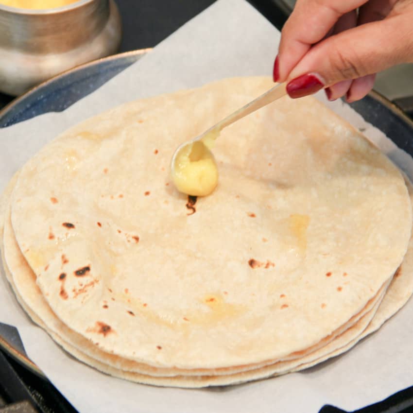 putting ghee on cooked roti 