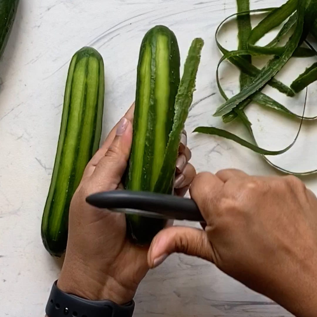 peeling small Persian cucumbers to koshimbir.