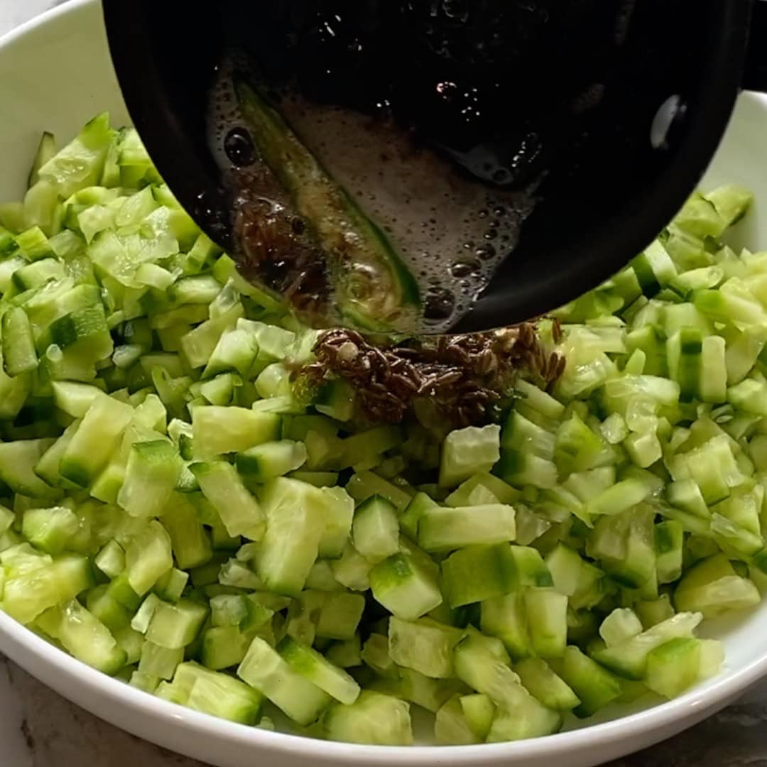 adding tadka to cucumbers.
