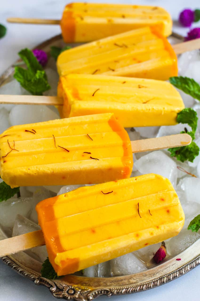 close up of a mango lassi popsicles on tray with ice