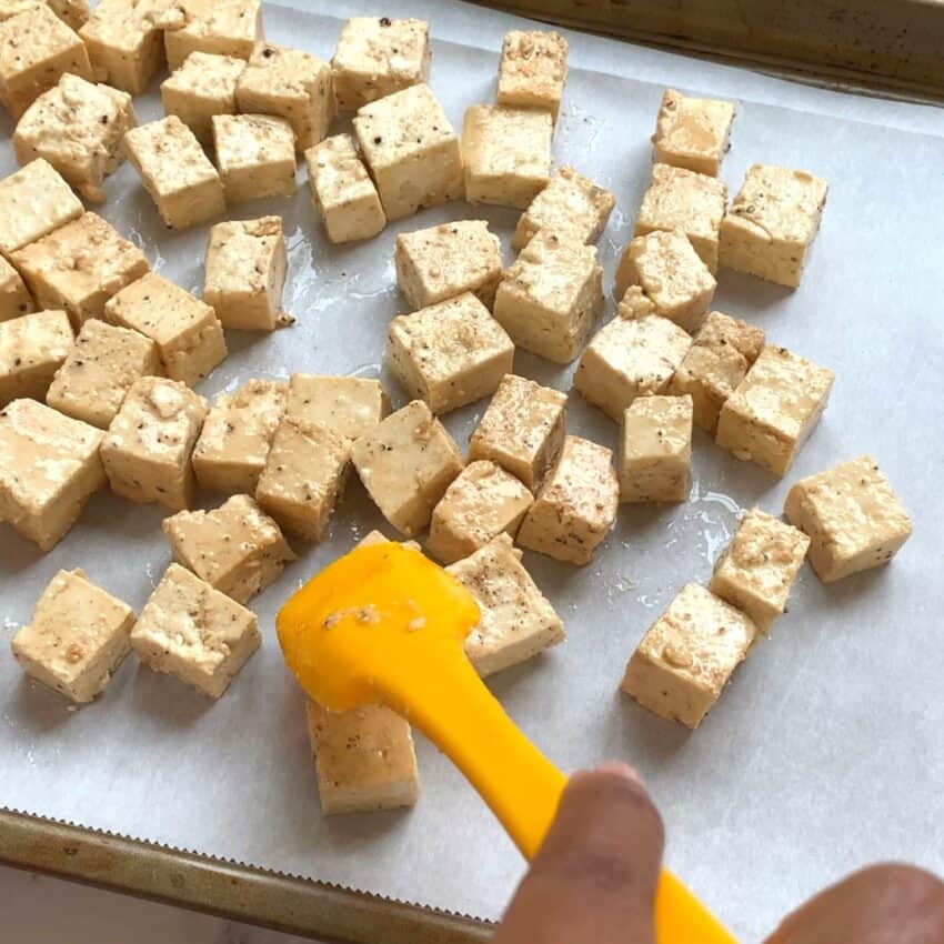 spreading tofu cubes on a baking tray