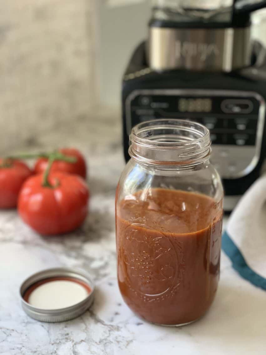 Enchilada sauce in a jar next to a blender 