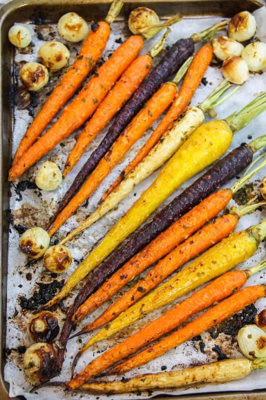 roasted carrots and pearl onions on parchment paper