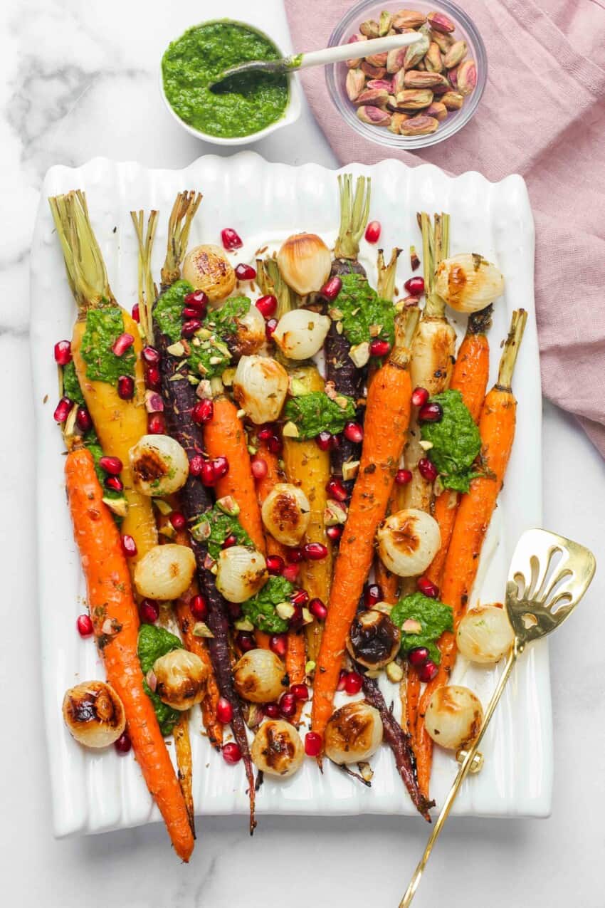 roasted carrots and pearl onions on white platter with small bowl of chutney